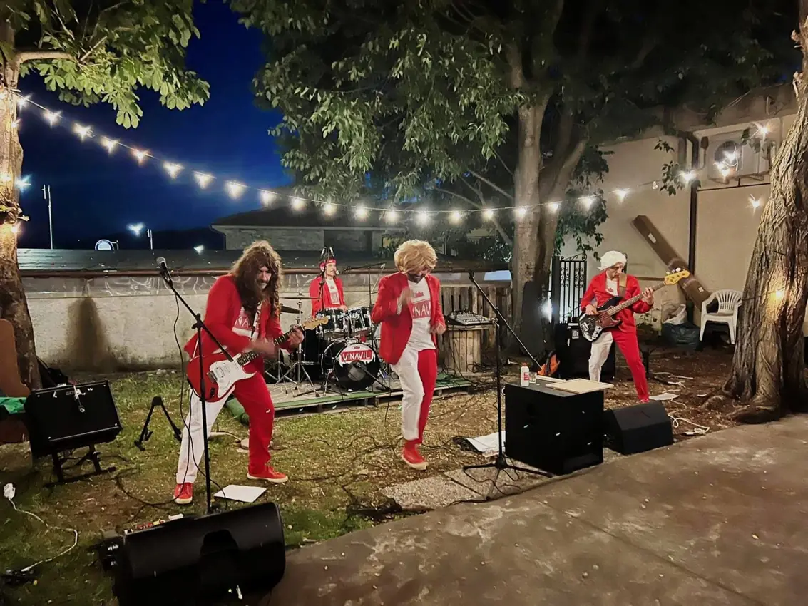 La band Vinavil si esibisce in concerto all'aperto, con costumi rossi
